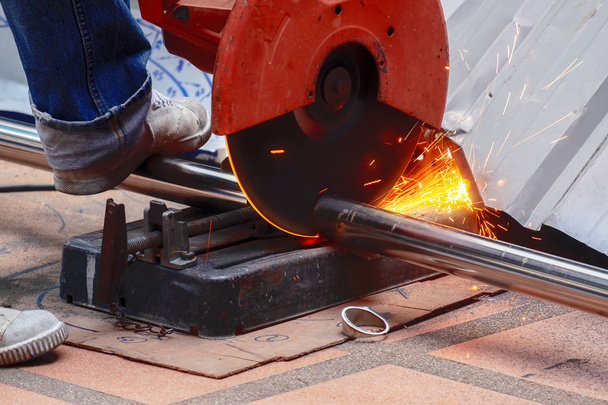Férfi dolgozó használata finomra vágjuk látta, hogy vágás a vastag rozsdamentes acél cső egy építkezésen munka. - Fotó, kép