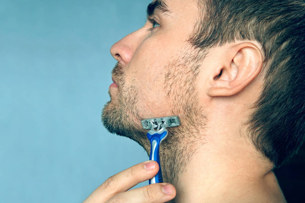 Egy férfi borotválkozó gépet borotválkozik hab, szappan és krém nélkül. Borotválkozz meg. Hirdetési plakát, szövegmásolási hellyel. másolótér. - Fotó, kép