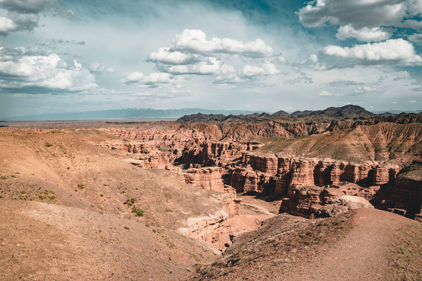 Charyn Grand Canyon with clouds and sun red orange stone Martian landscape - Фото, изображение
