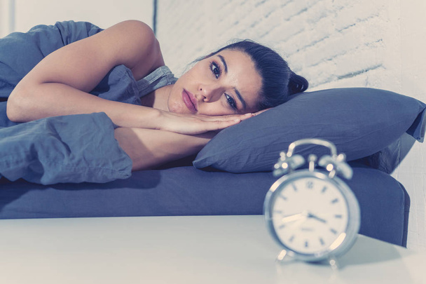 young beautiful hispanic woman at home bedroom lying in bed late at night trying to sleep suffering insomnia sleeping disorder or scared on nightmares looking sad worried in mental health concept - Photo, image