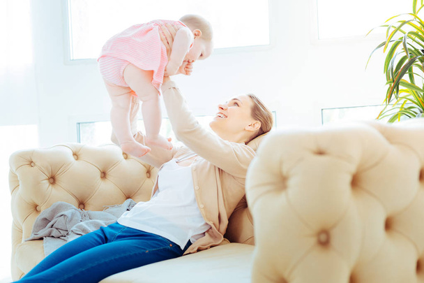 Positive delighted young female playing with her kid - 写真・画像