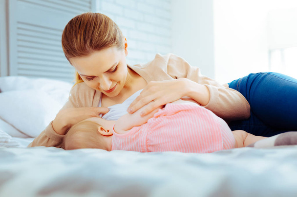 Attentive female person nursing her baby - 写真・画像