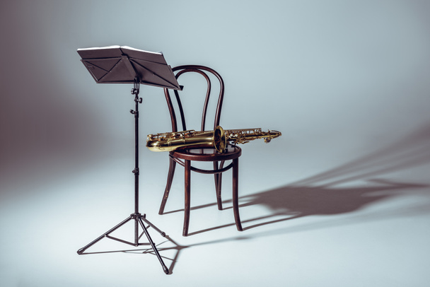music stand for notes and saxophone on chair in studio - Zdjęcie, obraz