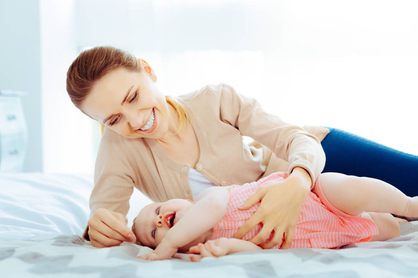 Cheerful blonde playing with baby girl - Foto, imagen
