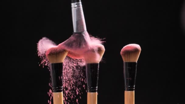 Makijaż i koncepcja piękna. Szczotka z różowym wybuchem proszku na czarnym tle - Materiał filmowy, wideo