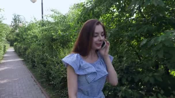 Piękna kobieta spaceru w parku i rozmawia przez telefon. - Materiał filmowy, wideo