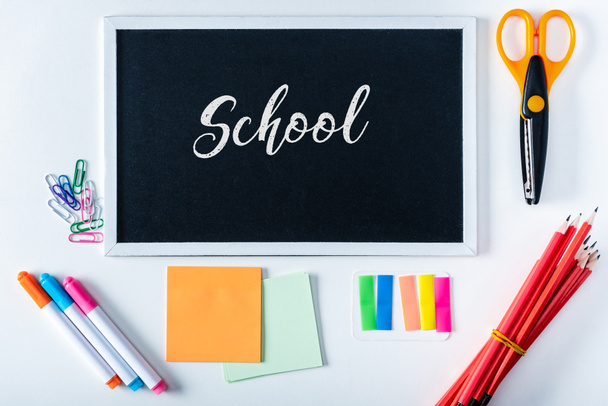 top view of chalkboard with lettering school and arranged variety stationery on white background - Fotografie, Obrázek