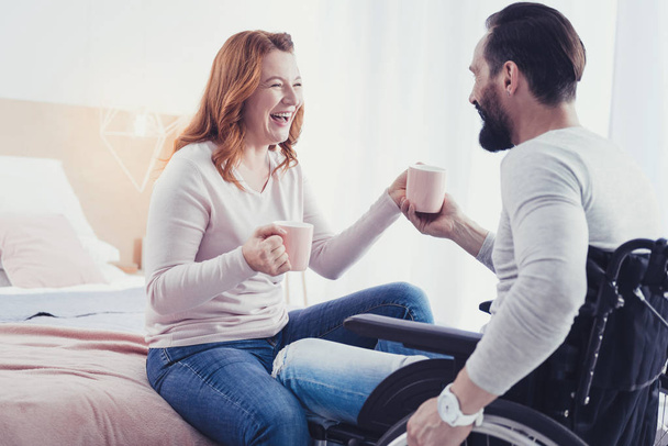 Emotional woman laughing while drinking tea with her disabled boyfriend - Foto, Imagem