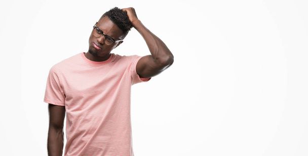 Afro-amerikai fiatalember visel rózsaszín póló összekeverik, és csodálkozom, hogy a kérdés. Bizonytalan a kétség, gondolt a kezét a feje. Töprengő koncepció. - Fotó, kép