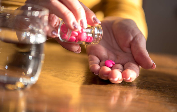 Close-up de mãos femininas tomando medicação, luz dura
 - Foto, Imagem
