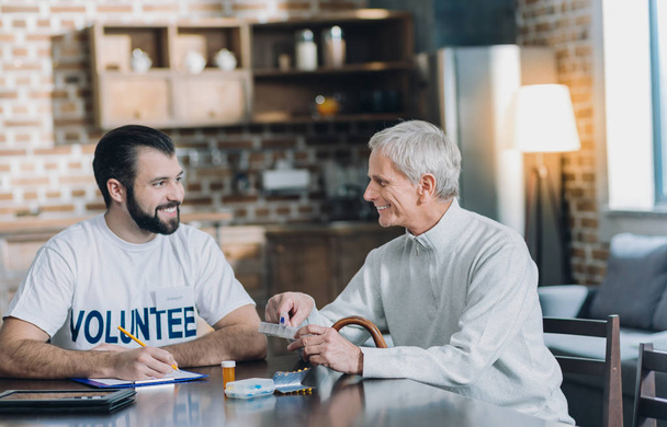 Happy volunteer having a nice talk with an old man - Photo, Image
