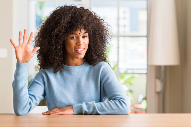 mujer afroamericana en casa mostrando y señalando hacia arriba con los dedos número cinco mientras sonríe confiado y feliz
. - Foto, imagen