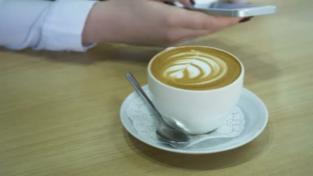 Woman using smartphone and drinking cappuccino. - Záběry, video