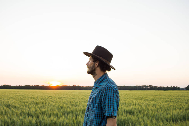 YOung male farmer stand alone in wheat field during sunset  - Foto, Imagen