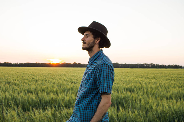 YOung male farmer stand alone in wheat field during sunset  - Foto, Bild