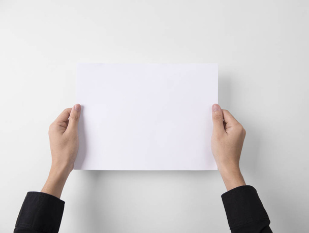hand met blanco papier A4 flyer voor mockup sjabloon logo branding op grijze achtergrond. - Foto, afbeelding