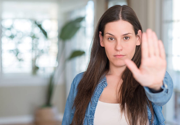 Młoda piękna kobieta w domu z otwartej dłoni robi znak stop z poważnych i pewnie wyrażenie, obrony gest - Zdjęcie, obraz