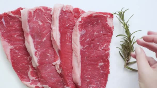 Raw New York strip steaks on a white background. - Footage, Video