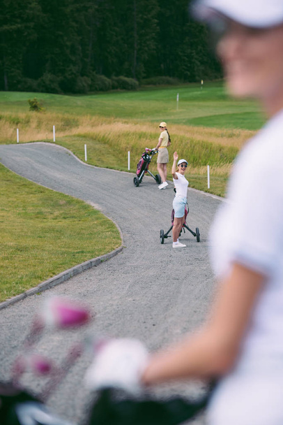 selectieve aandacht van vrouw in zonnebril met golf gear groet vriend op de golfbaan - Foto, afbeelding