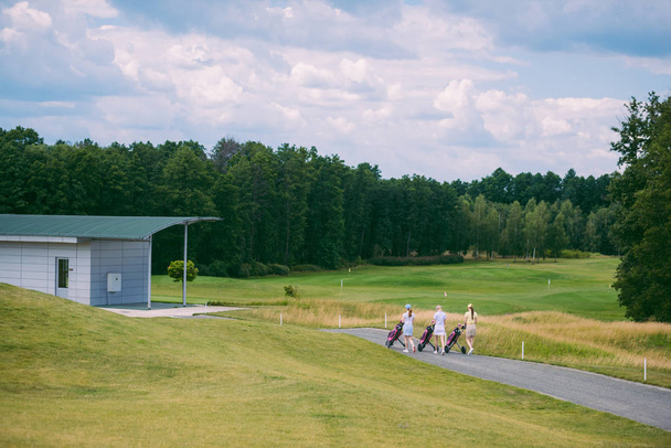 female golfers with golf gear walking at golf course on summer day - Foto, Bild