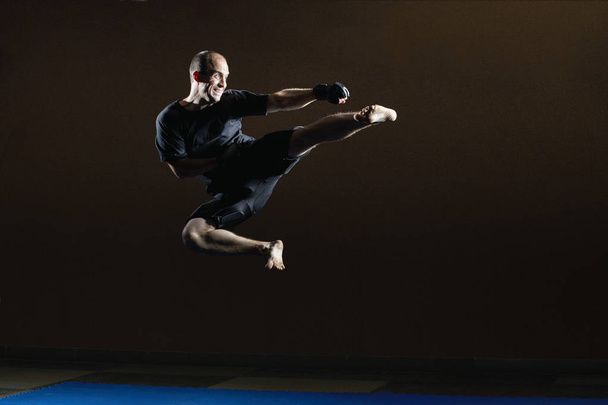 Kicking in a jump in the performance of an athlete in black gloves - Photo, Image