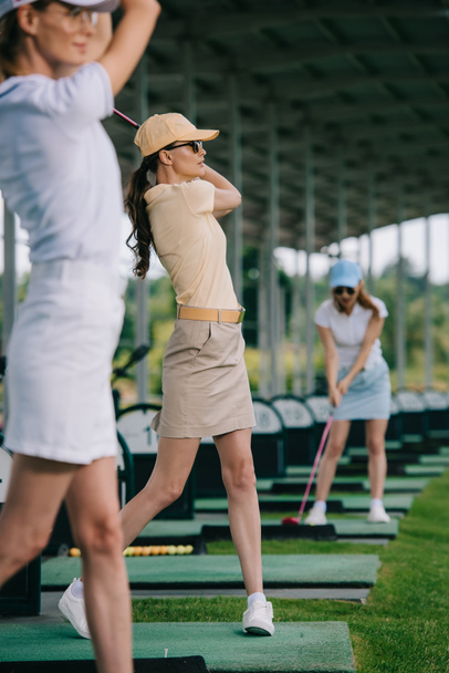 selective focus of women in caps playing golf at golf course - Photo, Image