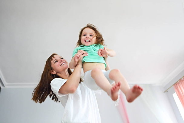 Young woman having fun with daughter indoors - Фото, зображення