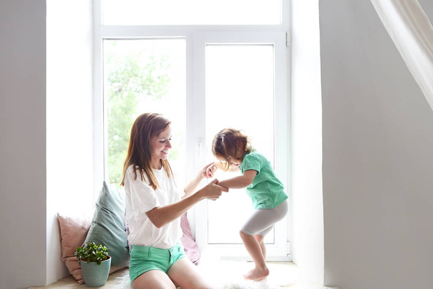 Молодая женщина развлекается с дочерью в помещении
 - Фото, изображение
