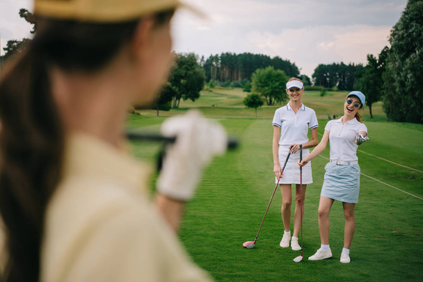 selective focus of smiling women with golf clubs at golf course - Foto, Imagem