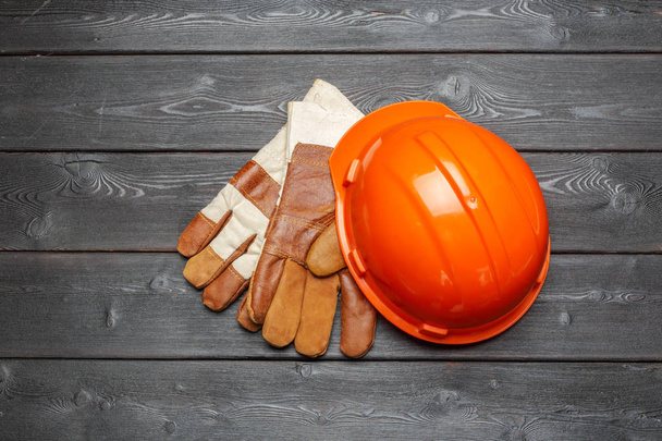 προστατευτικό κράνος και ένα ζευγάρι γάντια εργασίας σε μια ξύλινη επιφάνεια - Φωτογραφία, εικόνα