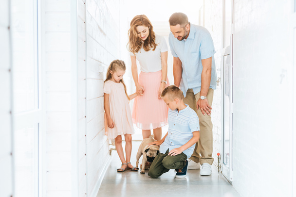 genitori e figli che guardano il cane carlino adottato nel corridoio del rifugio per animali
  - Foto, immagini