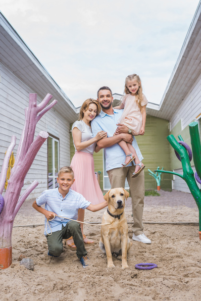 onnelliset vanhemmat ja lapset seisoo hyväksytty labrador koira eläinten suojassa
 - Valokuva, kuva
