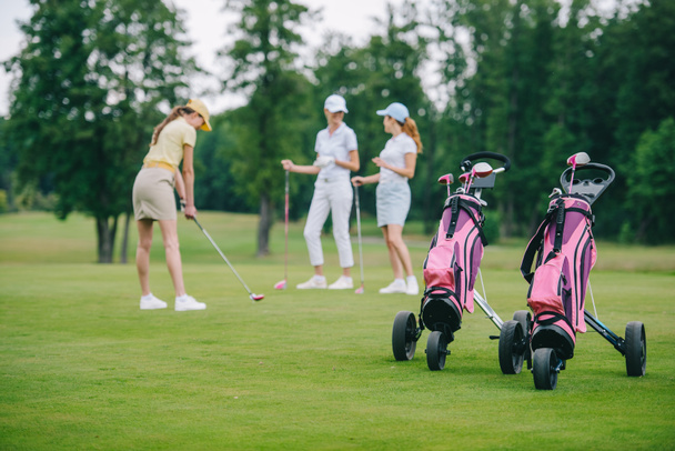 foyer sélectif de l'équipement de golf, femme en chapeau avec club de golf et amis se tenant à proximité au terrain de golf
 - Photo, image