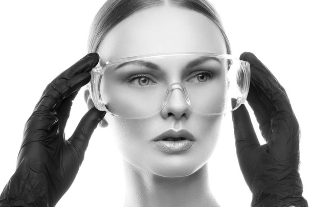 Portrait of young woman with natural makeup in eye-shield and surgical gloves - Foto, immagini