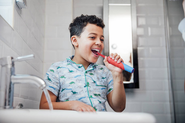 Little boy is brushing his teeth at the bathroom sink in the morning. - Foto, Imagem