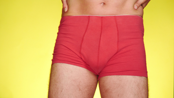 a man in red boxers dancing on a yellow background. close-up. 4k, slow motion - Footage, Video