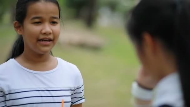 Aasialainen teini puhuu ystävänsä kanssa julkisessa puistossa
 - Materiaali, video