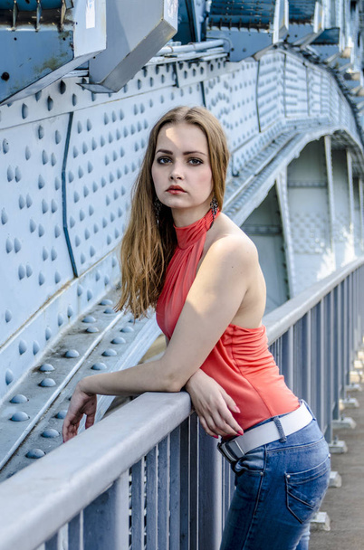 Beautiful young girl with long hair dreamily waiting at the bridge - Foto, Bild