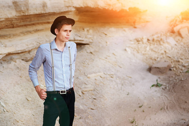 Homem elegante e atraente fica no meio de uma pedreira de areia e posa na câmera
. - Foto, Imagem