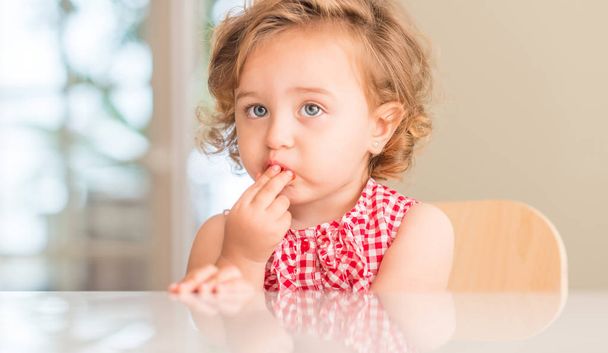Kaunis blondi lapsi sinisillä silmillä syö mansikkaa kotona
. - Valokuva, kuva