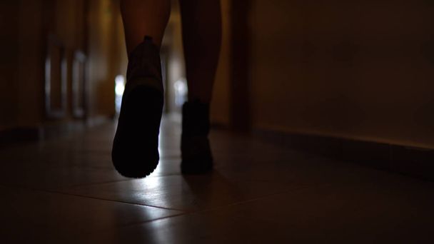 Dolly with low-section legs of silhouette woman running along corridor hallway in slow motion - Zdjęcie, obraz