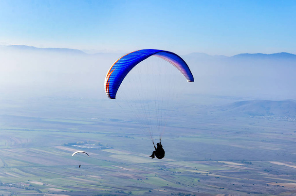Paragliders flying on blue sky background  - Foto, imagen