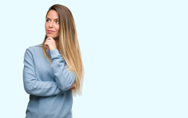 Beautiful young woman wearing sweater and jeans serious face thinking about question, very confused idea - Photo, Image
