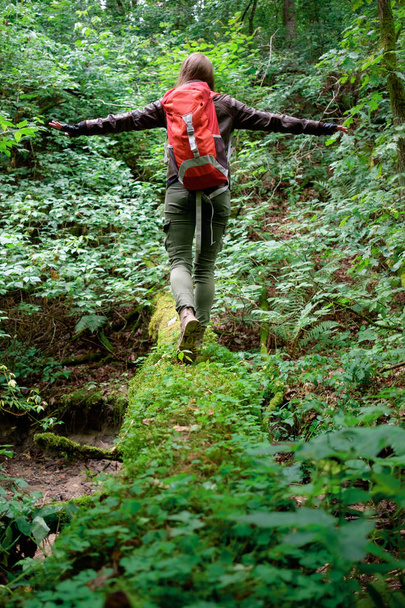 Jovem ruiva mulher de cabelo longo viaja com mochila de viagem vermelha na floresta nublada de verão. Viagens de conceito
. - Foto, Imagem