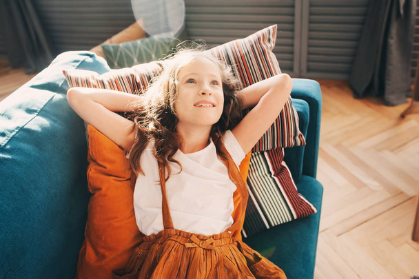 happy kid girl relaxing on cozy couch in modern living room.  - Foto, immagini