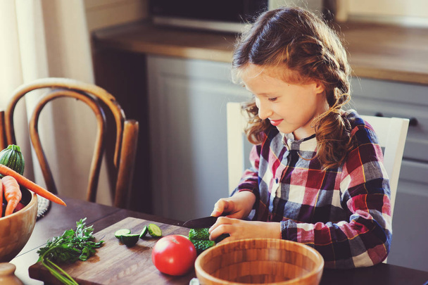 8 years old child girl help mom to cook vegetable salad at home. Healthy eating, little helper concept - Foto, Bild