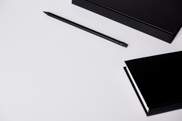 close-up shot of black hard cover notebooks with pencil on white tabletop - Foto, Imagem