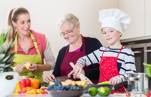 Nonna, mamma e figlio che parlano mentre cucinano in cucina
 - Foto, immagini
