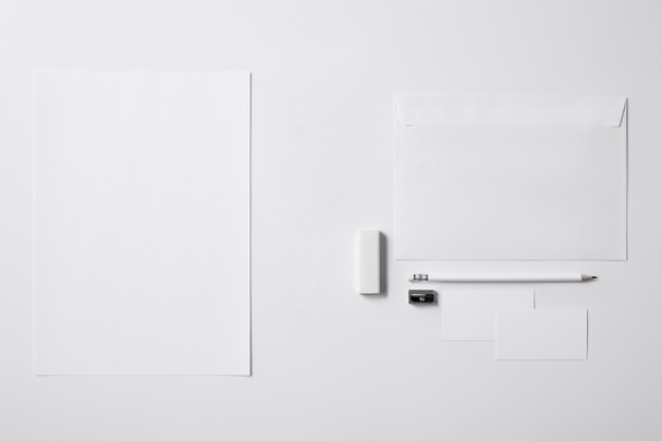 vista superior de vários objetos de papel e lápis com borracha e apontador na superfície branca para maquete
 - Foto, Imagem