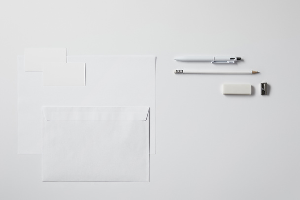 bovenaanzicht van verschillende objecten van papier en kantoorbenodigdheden op wit oppervlak voor mockup - Foto, afbeelding